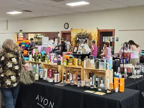 People browsing tables of products at an indoor vendor fair.