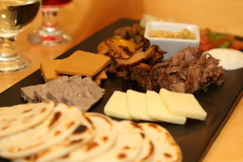 A charcuterie board with various cheeses, meats, crackers, and condiments.