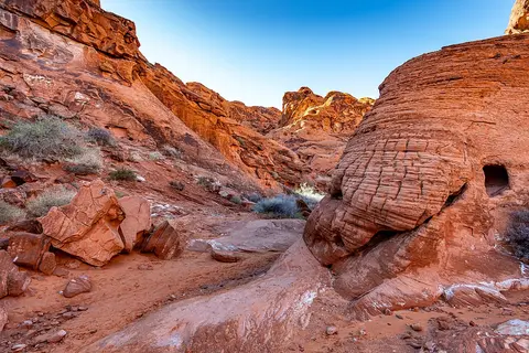 A red rock landscape with steep canyon walls under a clear blue sky.