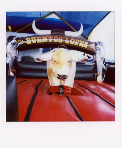 A mechanical bull sits inside a red inflatable arena.