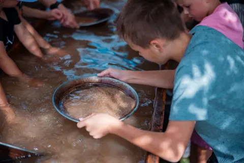 A child pans for gold in a water trough.