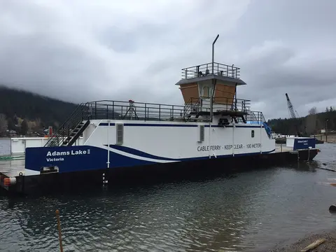 A white and blue cable ferry is on the water.