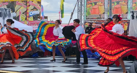 Performers dance in traditional costumes on an outdoor stage at a festival.