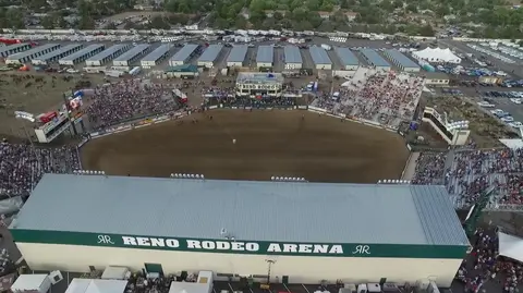An aerial view of a large rodeo arena with crowds and parked vehicles.