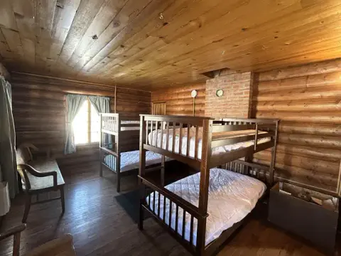A rustic wooden cabin room features bunk beds and wood-paneled walls.