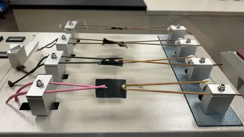 A testing machine holds four samples of cords and fabric in a laboratory.