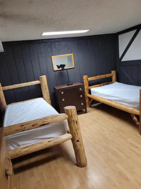 A bedroom featuring rustic log-style wooden beds and a dark paneled wall.