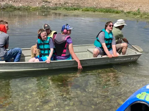 People ride in a metal boat on a calm body of water.