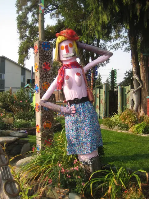A whimsical sculpture of a woman made from found objects stands in a garden.