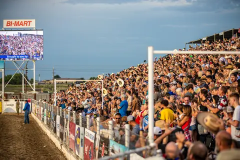 A large crowd watches an event from crowded outdoor grandstands.