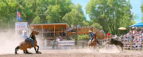 A rodeo event in an outdoor arena with spectators watching.