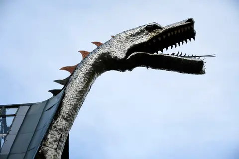 A close-up view of a metallic dragon sculpture against a plain sky.