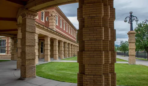An exterior view of a brick building with columns and a lamppost.