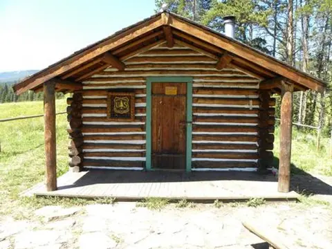 Exterior view of a small log cabin with a covered porch.