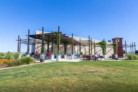 A large building with a covered outdoor patio and a green lawn in front.