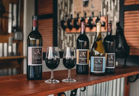 Several bottles of wine and two glasses stand on a wooden counter.