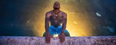 A man relaxes in a pool holding onto the edge.