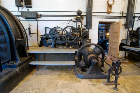 A vintage industrial machinery room with large gears and generators.