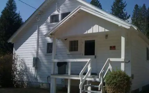 An exterior view of a small white building with a porch.