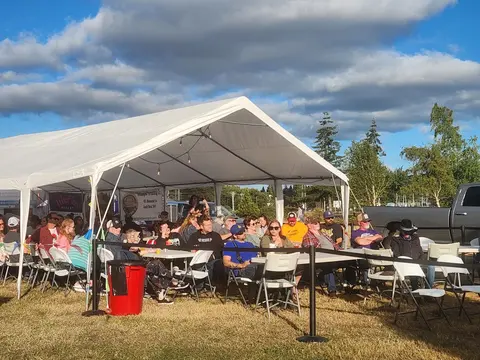 People seated under a large white tent outdoors.