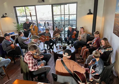 A group of musicians playing acoustic instruments in an indoor space.