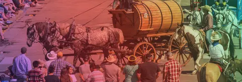 A horse-drawn wagon and riders move through a crowd at an outdoor event.