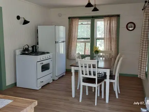 A brightly lit kitchen with a dining table, white stove, and refrigerator.