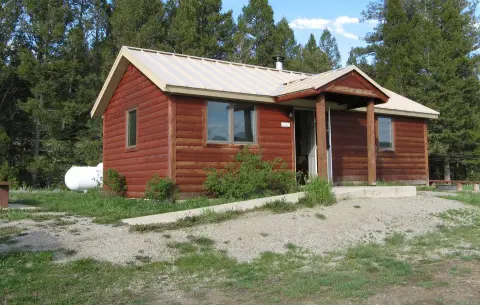 A red wooden cabin exterior surrounded by trees.