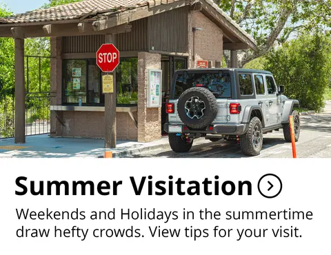 An SUV is parked at a park entrance booth on a sunny day.