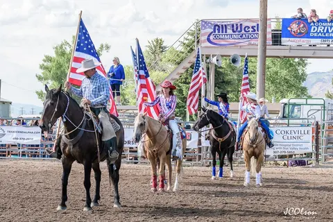 A group of people on horseback carrying American flags in an arena.