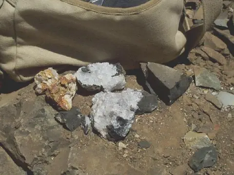 Rocks and crystals on the ground next to a canvas bag.