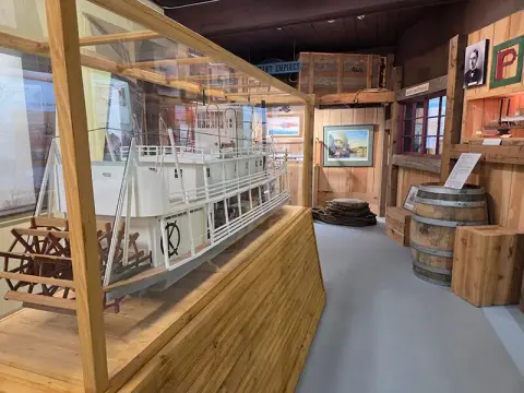 An interior museum exhibit featuring a model steamboat in a glass case.