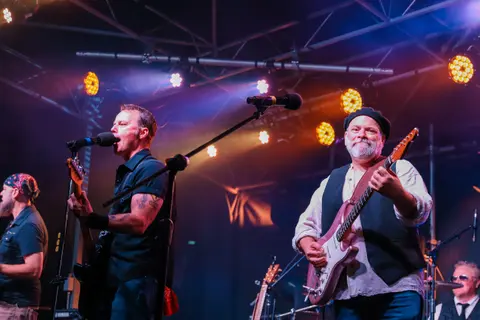 A band performs on stage with vibrant lighting.