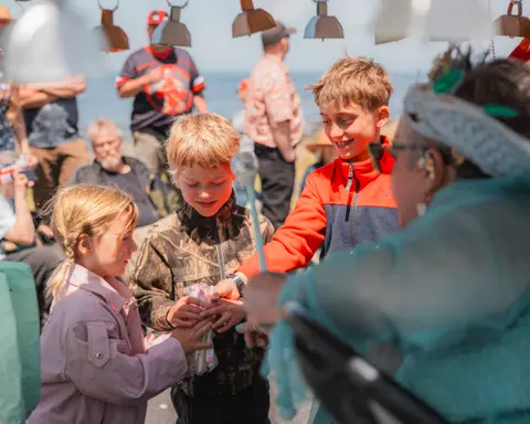 Children interacting with a vendor at an outdoor market or event.