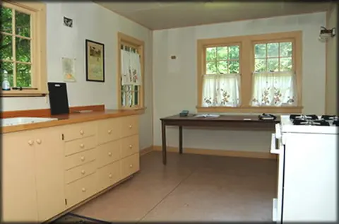 A bright interior room with kitchen counters and a table by windows.