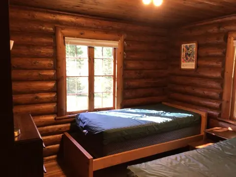 A bedroom inside a log cabin with two twin beds.
