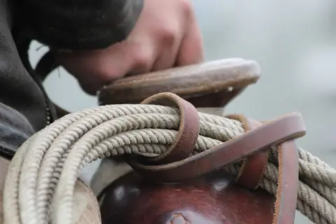 A close-up of a coiled rope secured on a saddle.