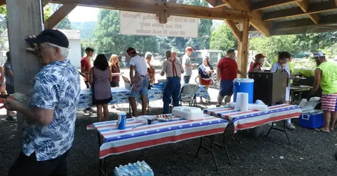 A group of people gather under a covered pavilion during an outdoor event.