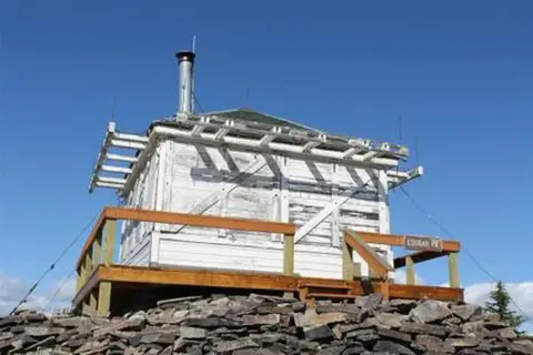 A small white building on a rocky platform against a blue sky.