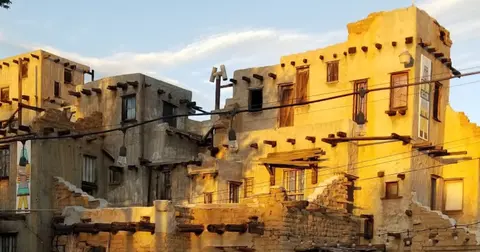 Exterior view of adobe-style buildings illuminated by warm sunlight.