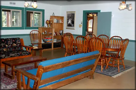 An interior view of a furnished common room with a couch, chairs, and dining table.