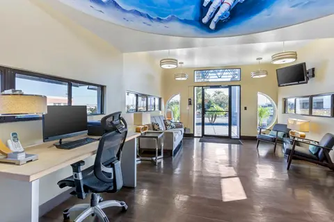 A brightly lit office or lobby with a desk, seating area, and an astronaut painted on the ceiling.