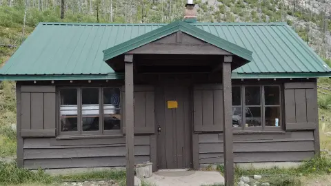 A small cabin with a green metal roof and a covered porch.