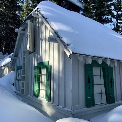 A wooden cabin covered in snow during winter.