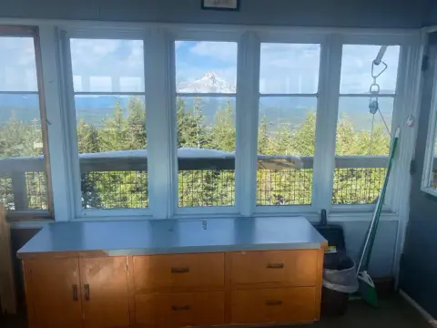 An interior view looking out a window at a snowy mountain peak and forest.