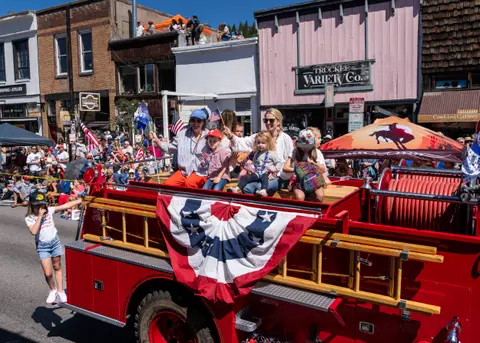 A group of people riding on a fire truck during a parade.