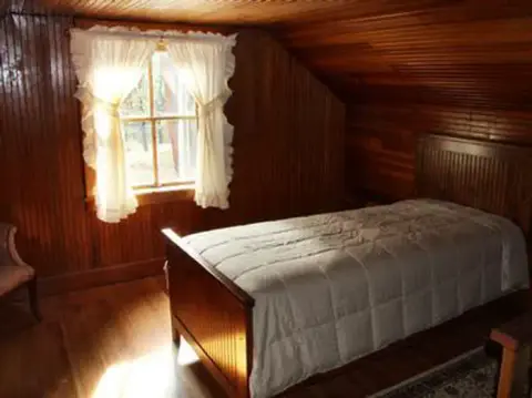 A bedroom with wooden panel walls and a single bed.