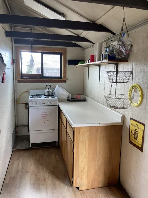 An interior shot of a small rustic kitchen with a stove and counters.