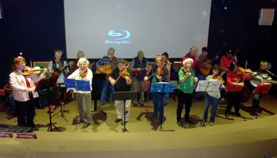 A group of musicians playing string instruments on a stage indoors.