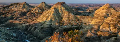 A landscape view of badlands formations illuminated by sunlight.